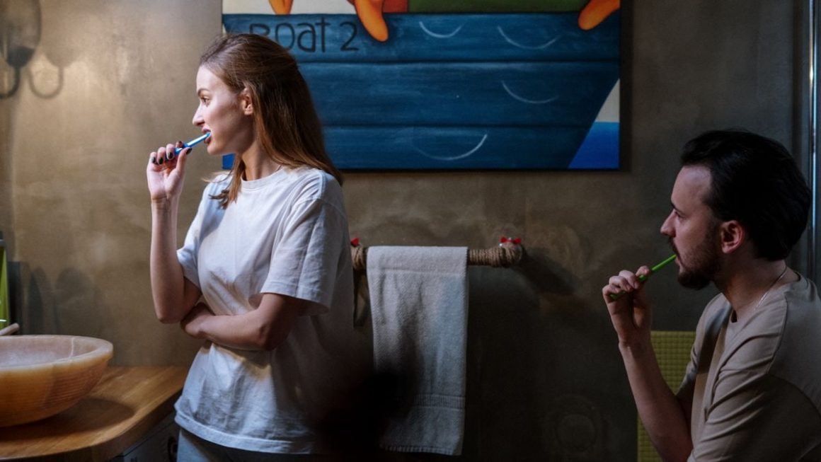 A couple brushing their teeth in a cozy bathroom during their morning routine.